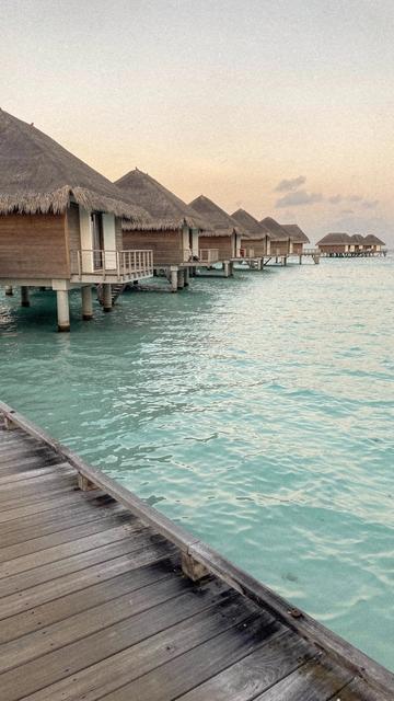 Over-water villas on a Maldivian atoll at first light, seen from the arrival jetty